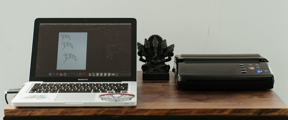 A printer, laptop, and figurine on a brown wooden table 
