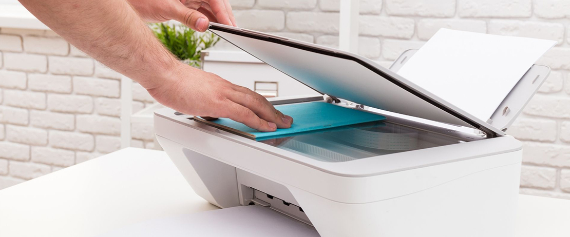 A person using a white printer/scanner 