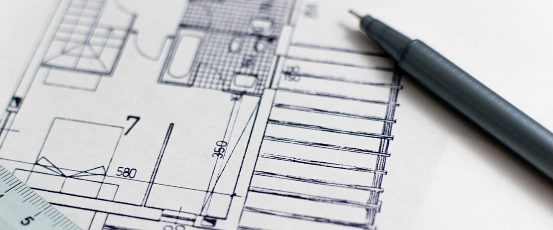 A black pen and a white ruler on top of a blueprint 