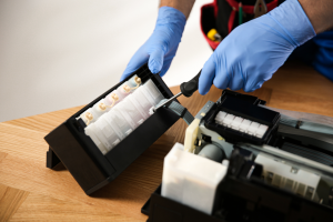 A person carefully removing ink cartridges from an old printer