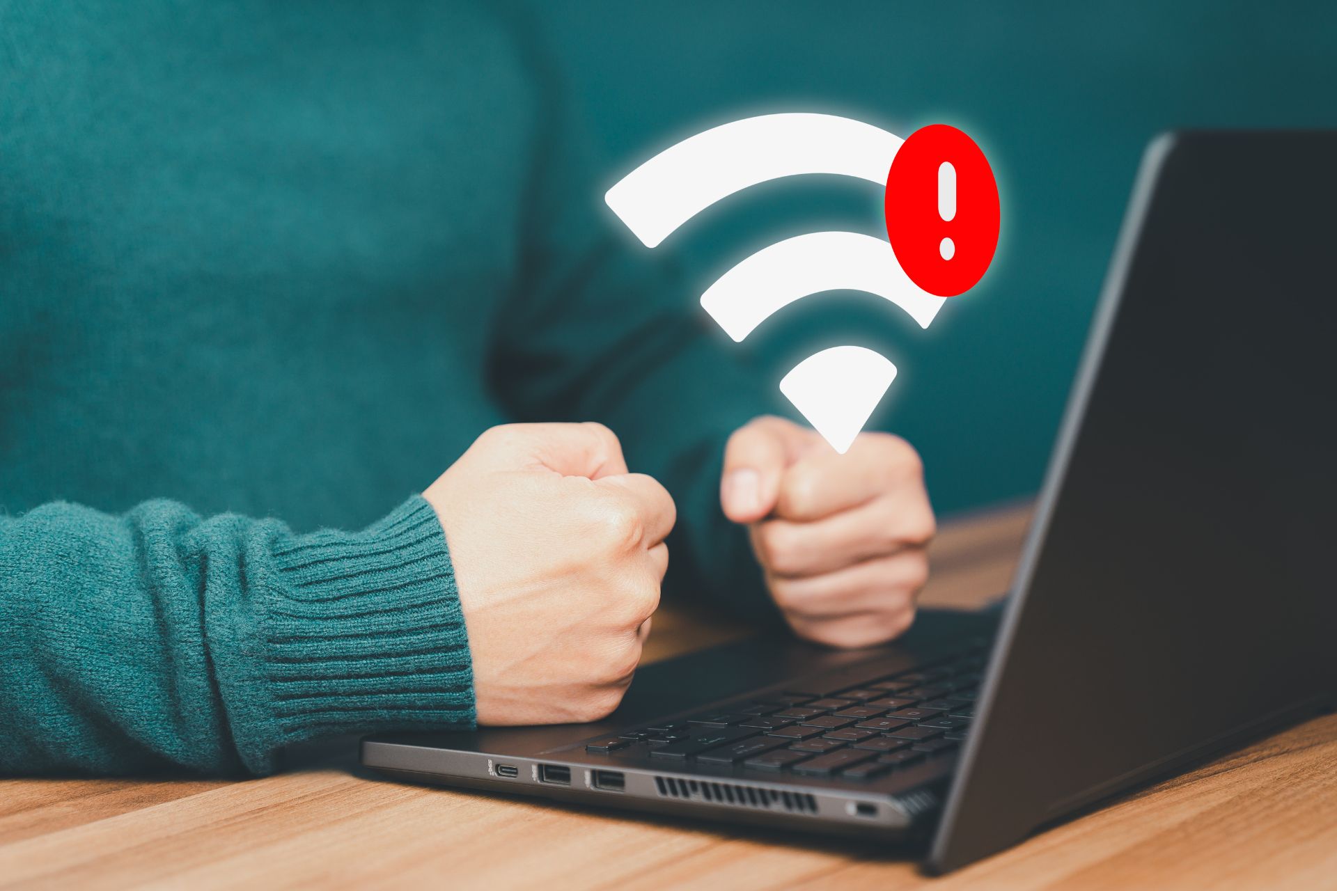 A person clenches their fists on their laptop with a Wi-Fi logo floating overtop, signalling a bad connection