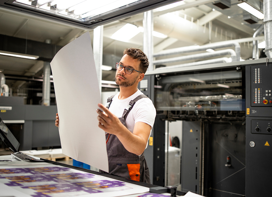 A man looks at a flat lay of printed packaging