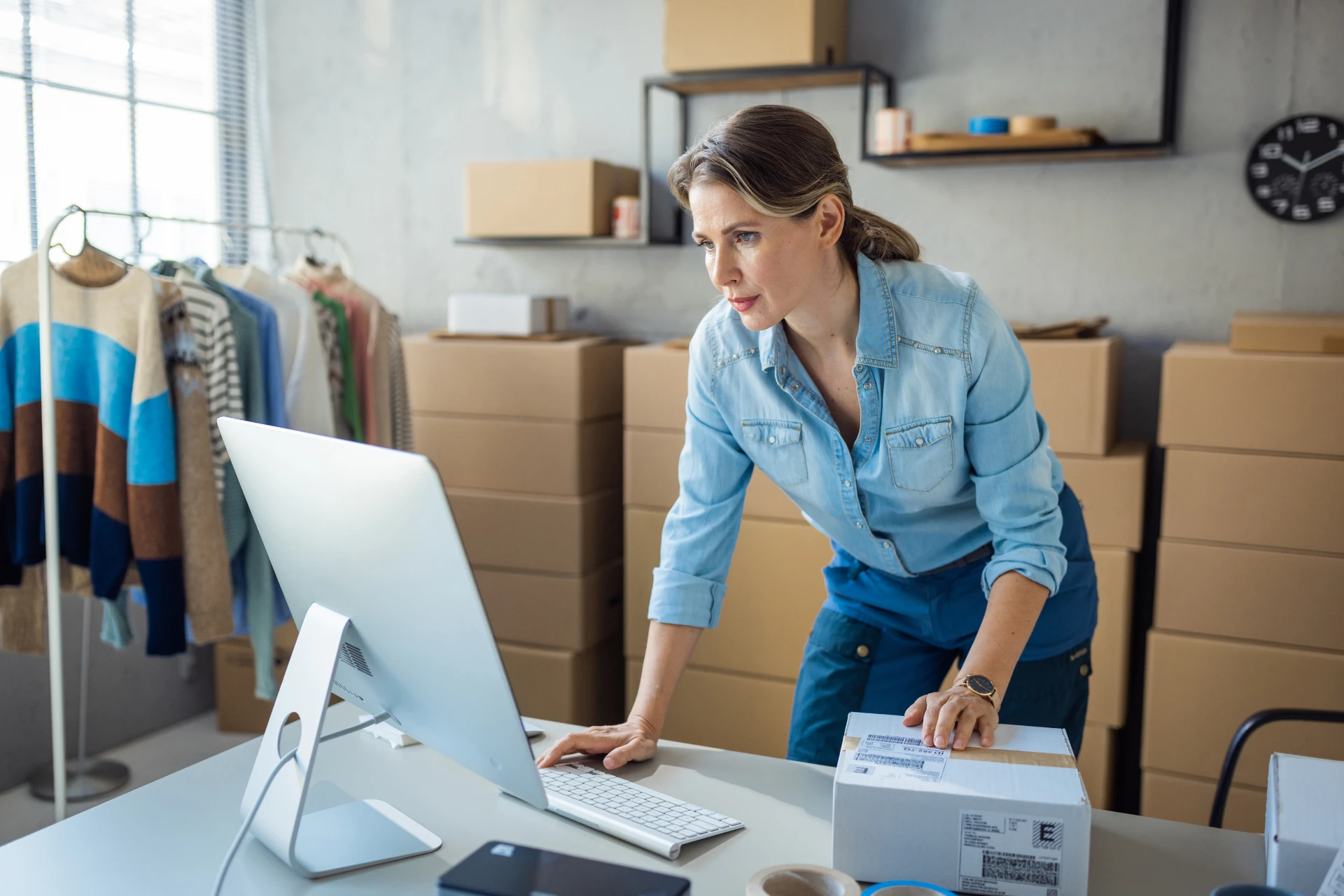 A small business owner using a computer while boxing parcels